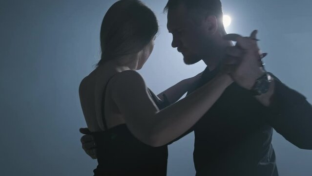 Professional couple of tango dancers posing in smoky studio with spotlights. Close-up of beautiful couple dancing latin dance in 4K, UHD