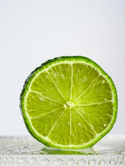 half a fresh lime in water drops on a white background
