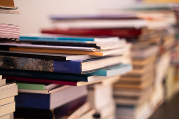 A large pile of books is stacked on a blurred background