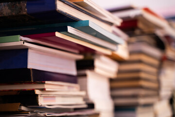 A large pile of books is stacked on a blurred background