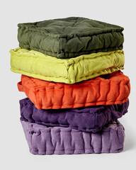 Stack of colorful decorative linen cushions against neutral background