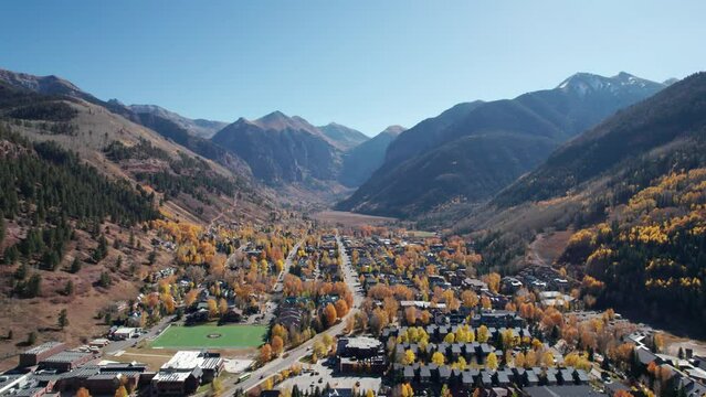 Distant pullback drone shot of downtown Telluride, CO with fall colors