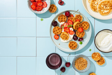 Sweet breakfast with mini waffles and fresh berries, strawberries and cherries. Top view.