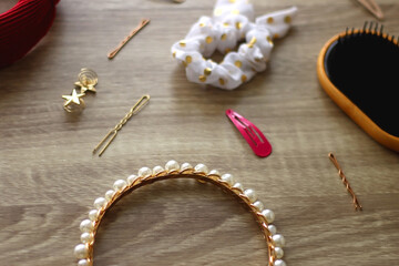 Wooden hairbrush, scissors and various headbands, hair clips and scrunchies on wooden background. Selective focus.