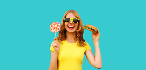 Portrait of happy cheerful young woman with burger fast food and sweet lollipop