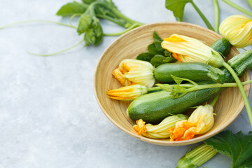 Young zucchini with flowers in a bowl, close-up, selective focus. Copy space.