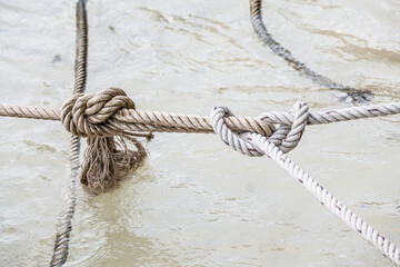 Close view of rope knot against sea water and rock background