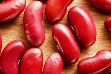 Macro shot of a detailed view of a small group of uncooked red beans on a wooden background. Top view.