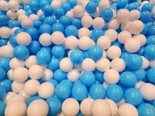 In the children's playground there are many small white and blue plastic balls arranged for children to play with for recreation. Hollow plastic ball texture background. Play toy for kids activity. 
