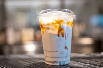 Cold fresh milk caramel macchiato on table, bokeh light background