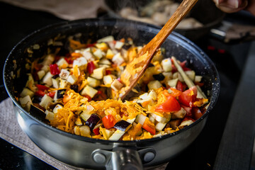 skilled chef preparing a classic French ratatouille salad in a sizzling frying pan.