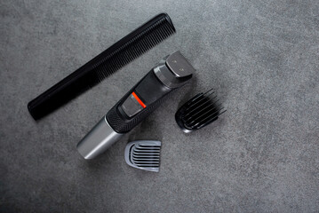 Wireless hair trimmer and beard on gray stone background