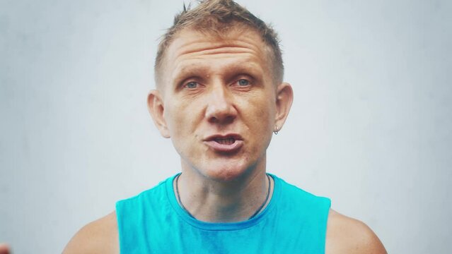 Man talks. Caucasian middle aged male talks on camera during interview on the grey background