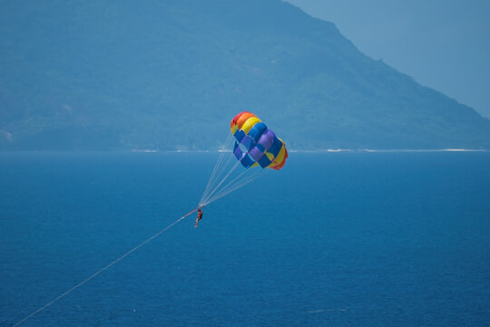 Single person paragliding from boat at beau vallon beach, Mahe, Seychelles 