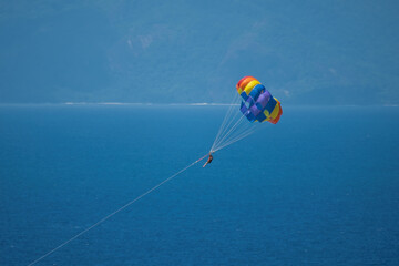 Single person paragliding from boat at beau vallon beach, Mahe, Seychelles 