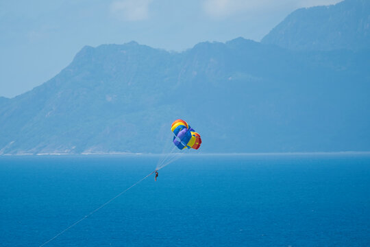 Single person paragliding from boat at beau vallon beach, Mahe, Seychelles 