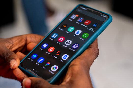 Lugbe, Abuja/Nigeria - December 17 2023: black person holding their android phone, with screen showing a variety of apps