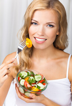 Portrait image - smiling blond blonde woman holding glass bowl with vegetable salad home house interior, indoors. Healthy eating, vegetarian, keto ketogenic diet concept.