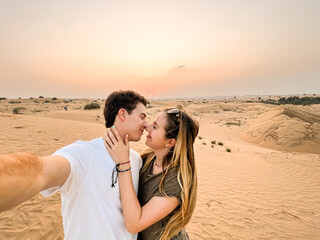 Selfie photo of young traveling tourists couple in love in the Dubai desert, United Arab Emirates