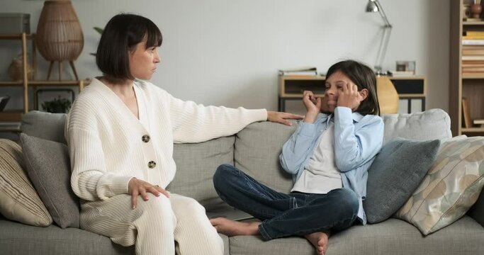 Caucasian angry mother scolding naughty son addicted to modern technology or video games at home living room. Mother and son conflict, bad family relationships, parenthood problems.