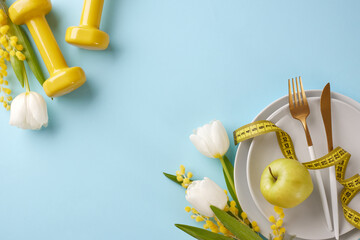Fresh and fit: a guide to shedding winter pounds this spring. Top view shot of plates, cutlery, green apple, yellow dumbbells, measure tape, fresh flowers on pastel blue background with promo zone