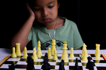 Little girl playing chess on black background Selective focus and shallow depth of field