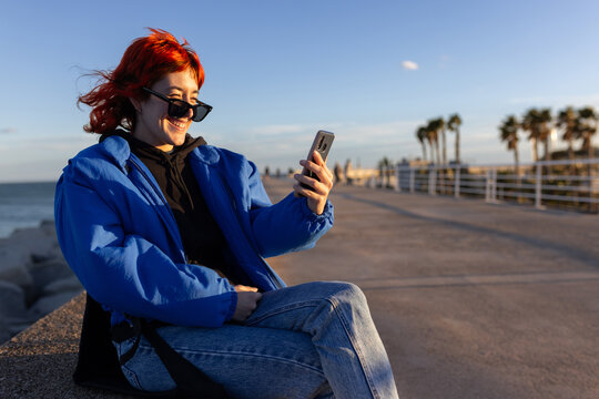 Red Hair Woman Smiling Looking at Camera at Sunset with Blue Jacket,Reading book smiling, looking at phone, taking pictures looking through phone