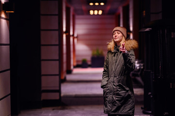 Woman takes a contemplative walk in an illuminated city alley at night, with warm lights above