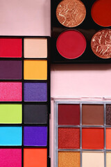 Various colorful eyeshadow palettes on bright pink background. Flat lay.