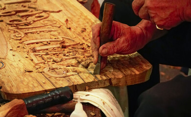 Hands of Carver man carving on wood wall with chisel and hammer for gouge work, A skillful...