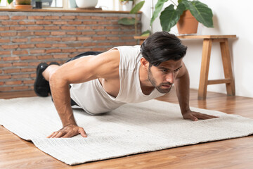 sporty young man make an exercise plank in the living room at home to bodybuilding.
