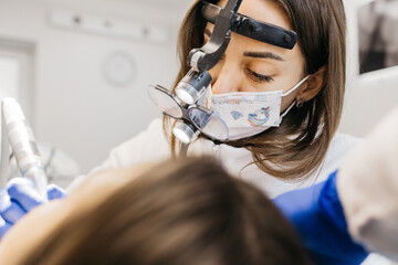 A young woman is undergoing treatment in a modern dental clinic. The concept of dental treatment, whitening, installation of veneers and braces, cleaning the oral cavity. - obrazy, fototapety, plakaty