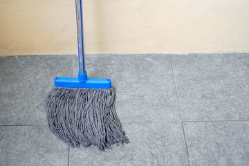 a simple floor mop propped against the wall