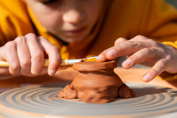 Concentrated child shaping a piece of pottery on the wheel