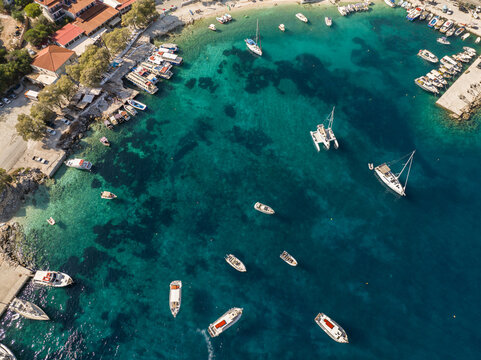  Port on a Greek island with blue turquoise water with many boats and yachts on the water in Greece, Zakynthos. Aerial drone photo of Agios Nikolaos - a small port on the island of Zante.