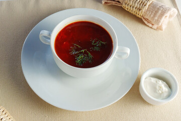 Presented bowl of creamy tomato bisque soup, adorned with a gleaming silver spoon.