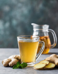 Ginger tea in a glass cup with fresh ginger root on a blurred background