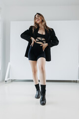portrait of a young blonde beautiful business woman sitting on a directors chair in black skirt, jacket and boots