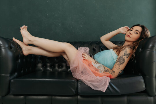 portrait of a young blonde beautiful woman posing on a couch in a pink dress