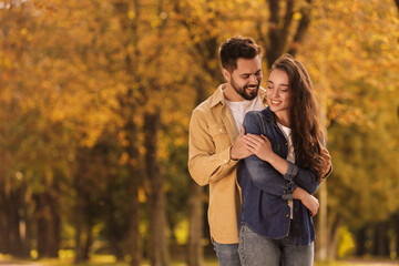 Beautiful couple spending time together in autumn park, space for text