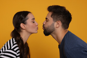 Cute young couple kissing on orange background