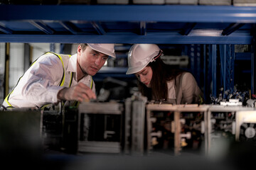 checking and inspecting metal machine part items for shipping. male and woman worker checking the...