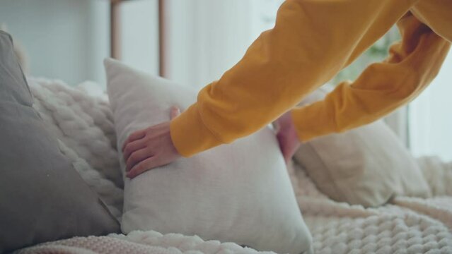 Hands of woman arranging pillows on comfortable sofa cushions at home, household, housework and cleaning concept