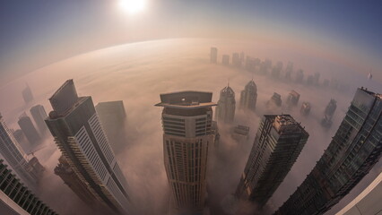 Rare early morning winter fog above the Dubai Marina skyline and skyscrapers lighted by street...
