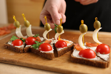 Olives and onions are added to the sandwich. Preparation of canapes with fish and vegetables