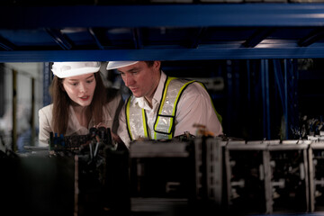 checking and inspecting metal machine part items for shipping. male and woman worker checking the...