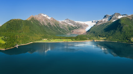 A panoramic summer vista of Svartisen Glacier nestling in the Saltfjell mountain range, reflected...