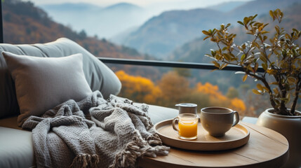 Wide panoramic closeup background banner photo, view from a luxury hotel bedroom window, cozy couch with pillows and coffee cup on a tray, misty mountain range landscape outside in a cold day morning
