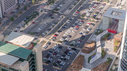 Fototapeta premium Aerial view of many colorful cars parked on parking lot with lines and markings for parking places all day timelapse. Dubai