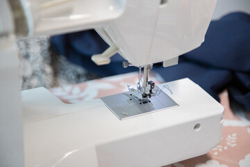 Close-up view of the components of the sewing machine, part of the needle with the thread and the presser foot.